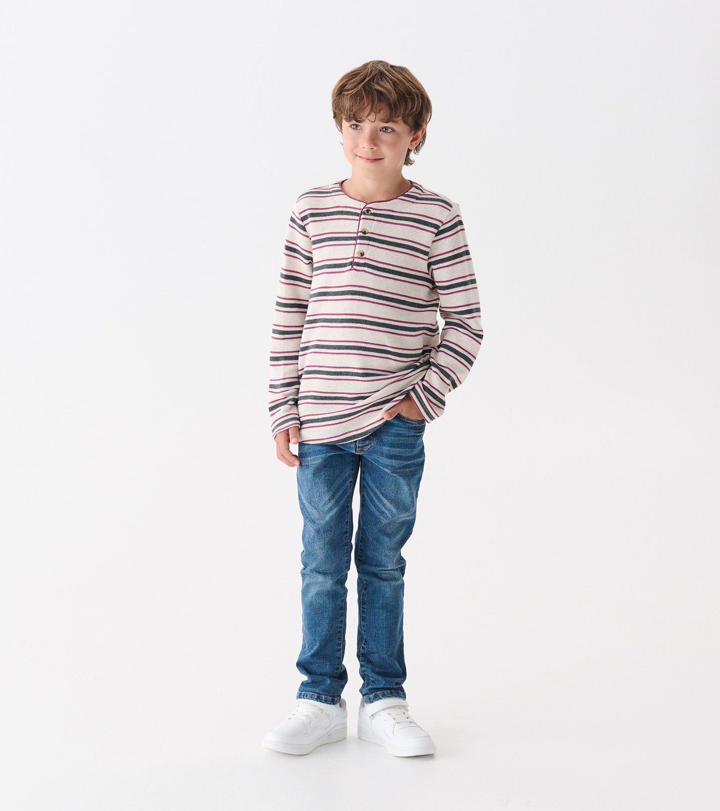 Classic blue jeans for boys, featuring a slim fit and a medium wash, paired with a striped long-sleeve shirt.