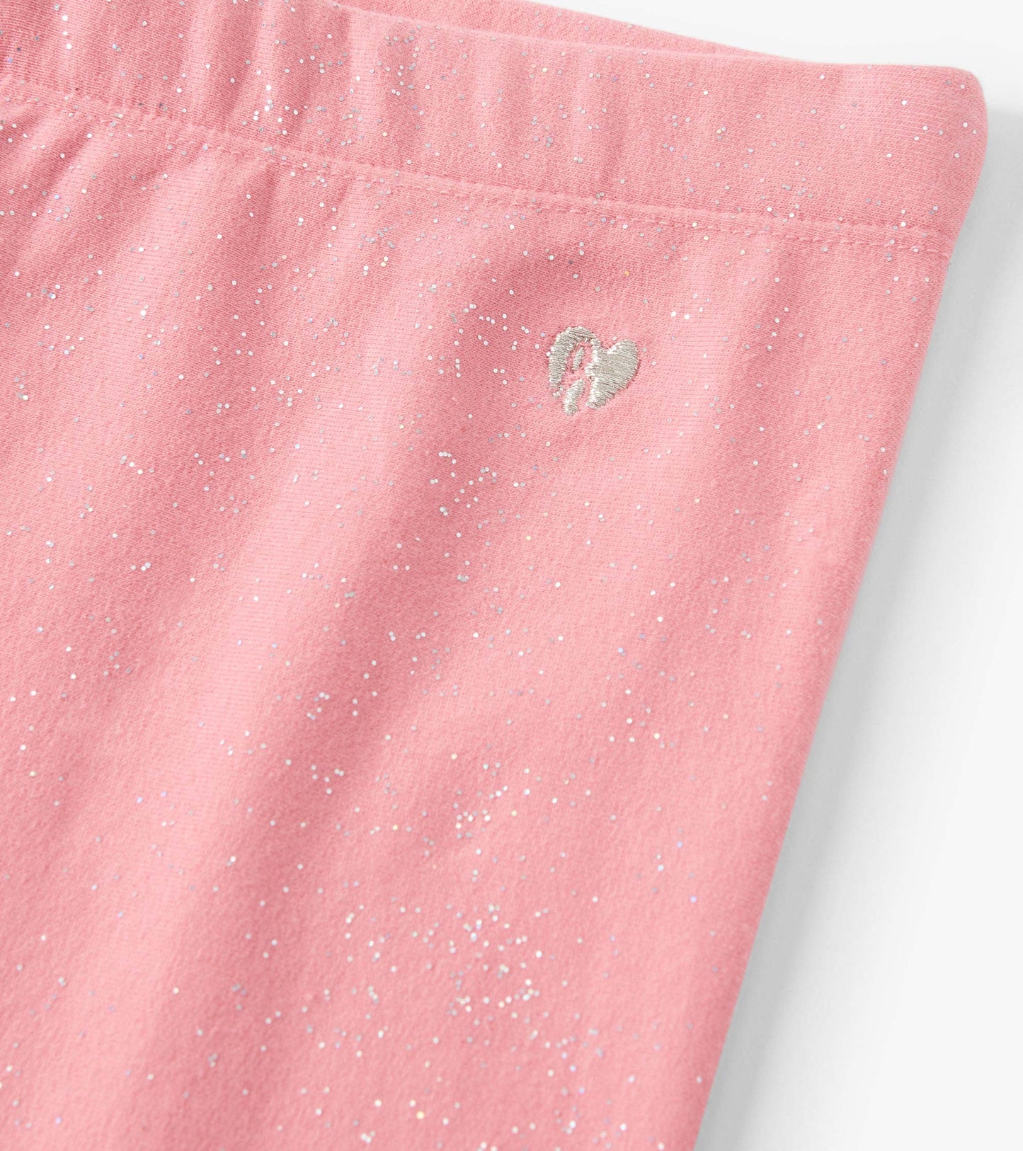 Pink cozy leggings with a glittery pattern and a small heart embroidery detail.
