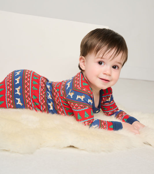 Red and blue Fair Isle footed sleeper with dog and tree patterns, suitable for infants, shown on a soft surface.