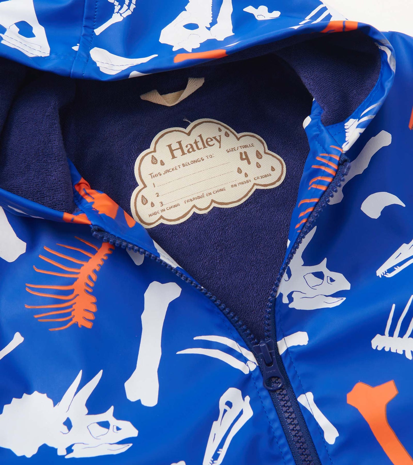 Blue zip-up raincoat featuring white and orange dinosaur fossil prints, with a soft navy lining inside the hood.
