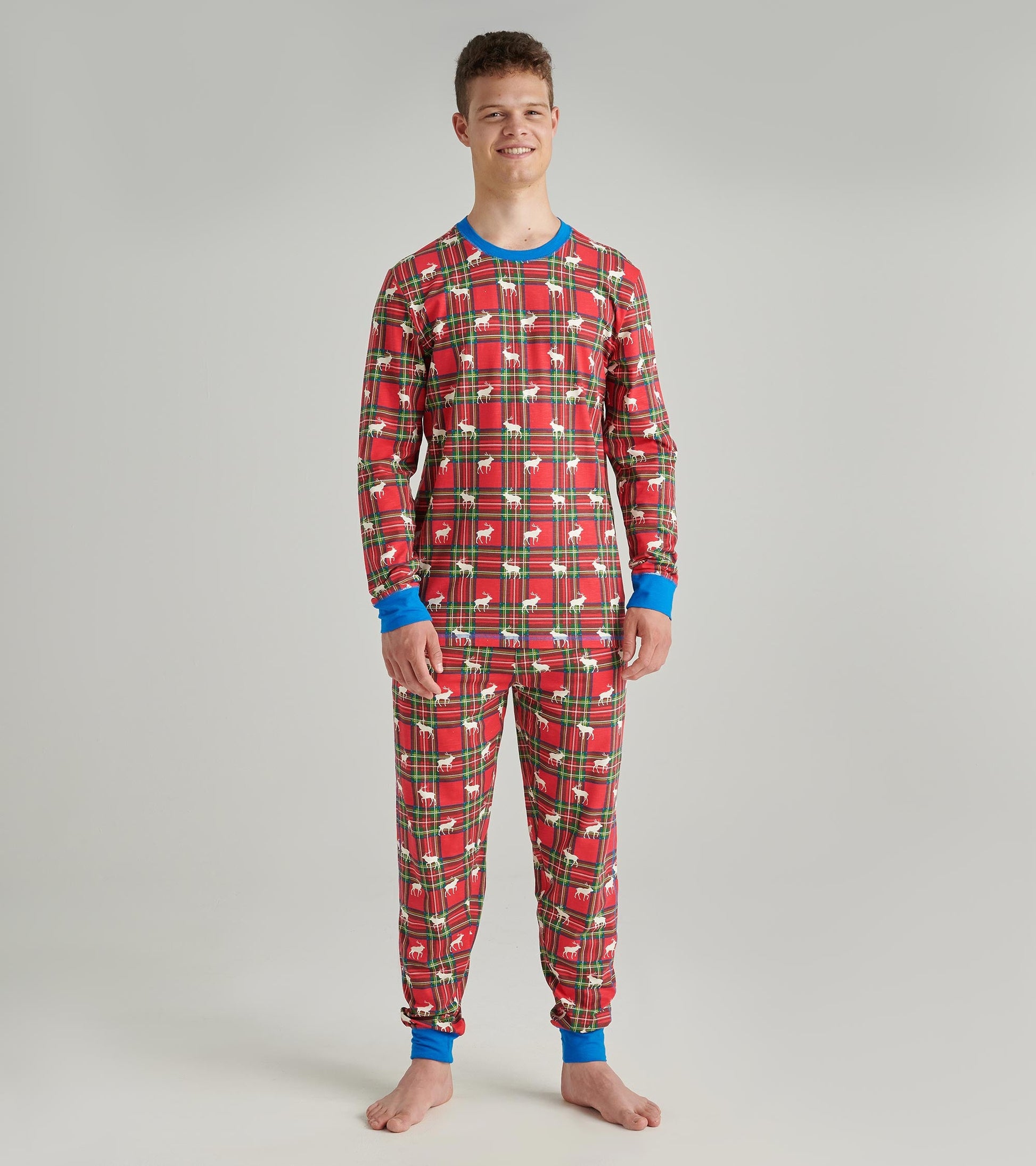 Red plaid pyjama set with blue cuffs, featuring a festive pattern of deer and trees, suitable for lounging or sleeping.