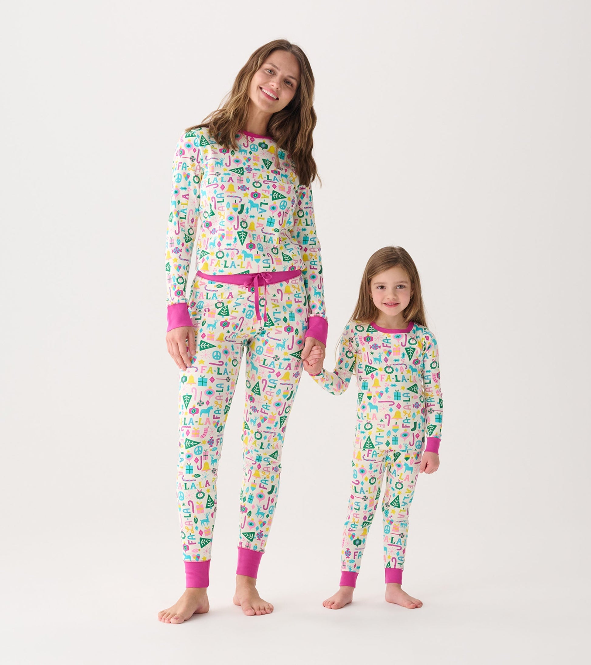 Matching women's and girl's pink pajama sets with colorful patterns, featuring long sleeves and elastic cuffs.
