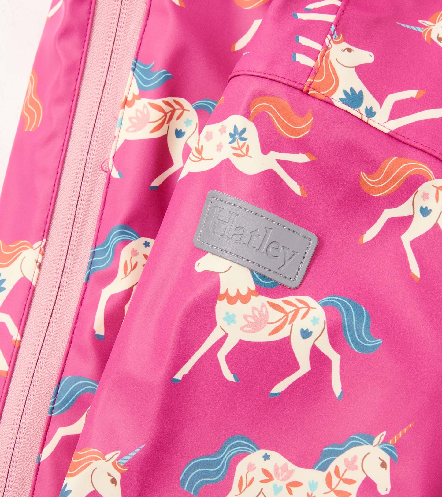 Pink rain suit featuring a whimsical unicorn pattern, with a front zipper and a small logo patch.