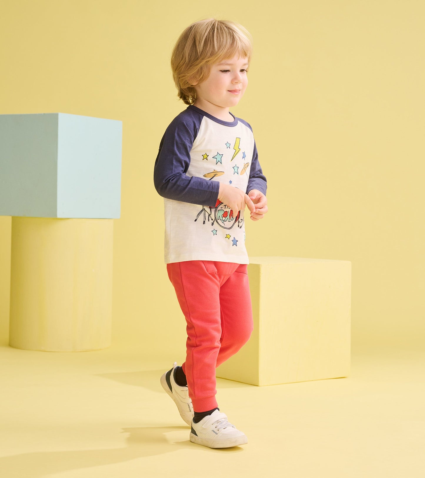 Long sleeve white t-shirt with navy sleeves, featuring a colorful drum kit graphic, paired with pink pants.