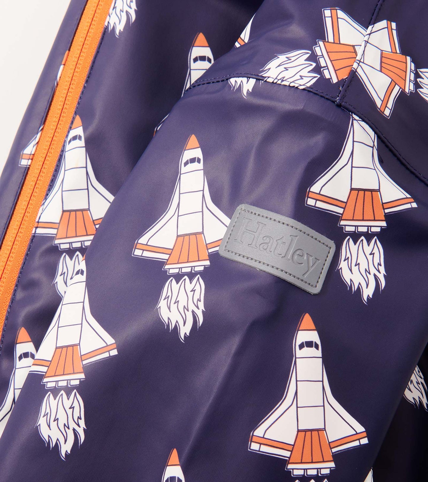 Navy rain suit featuring colorful space shuttle prints and an orange zipper, designed for baby boys.
