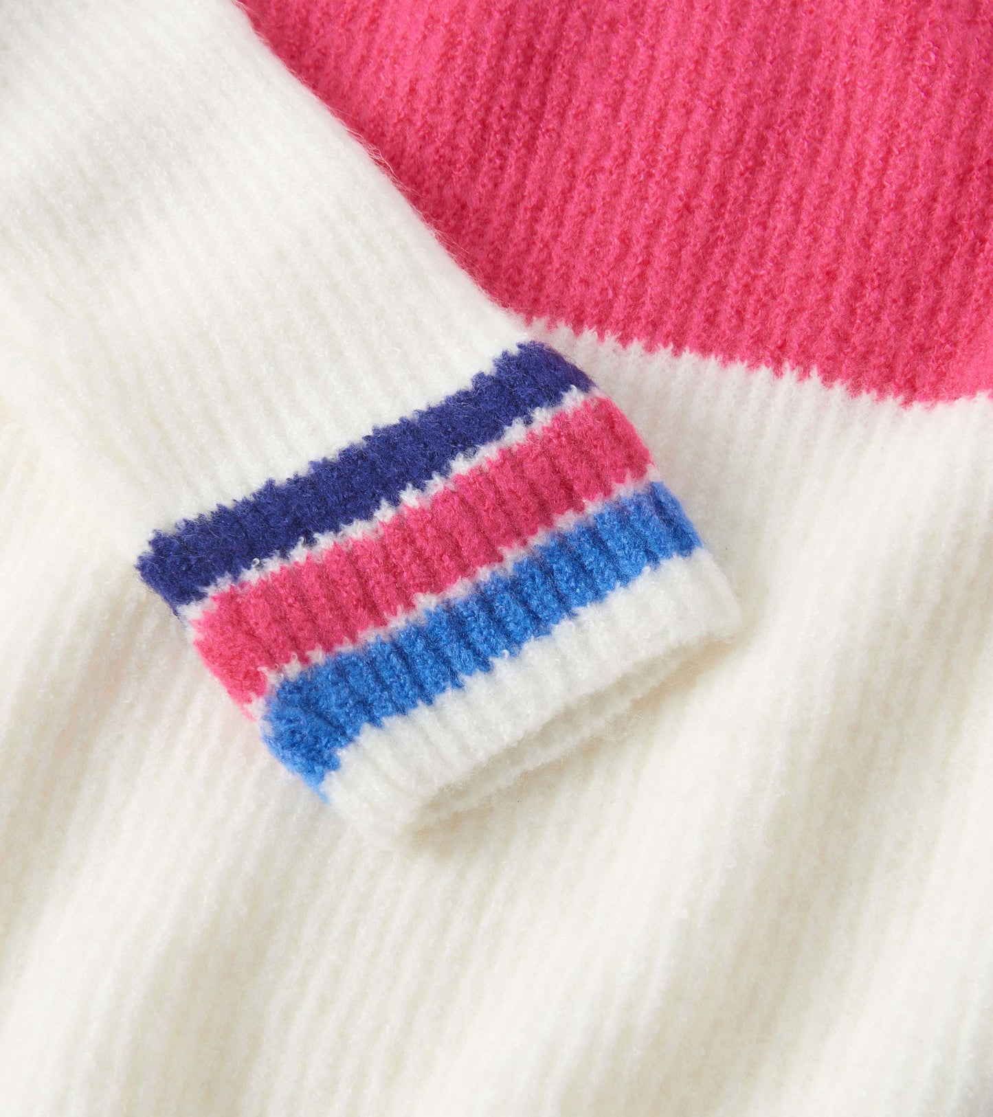 Colourblock mockneck sweater featuring white, pink, and multicolored striped cuffs, made from soft knit material.