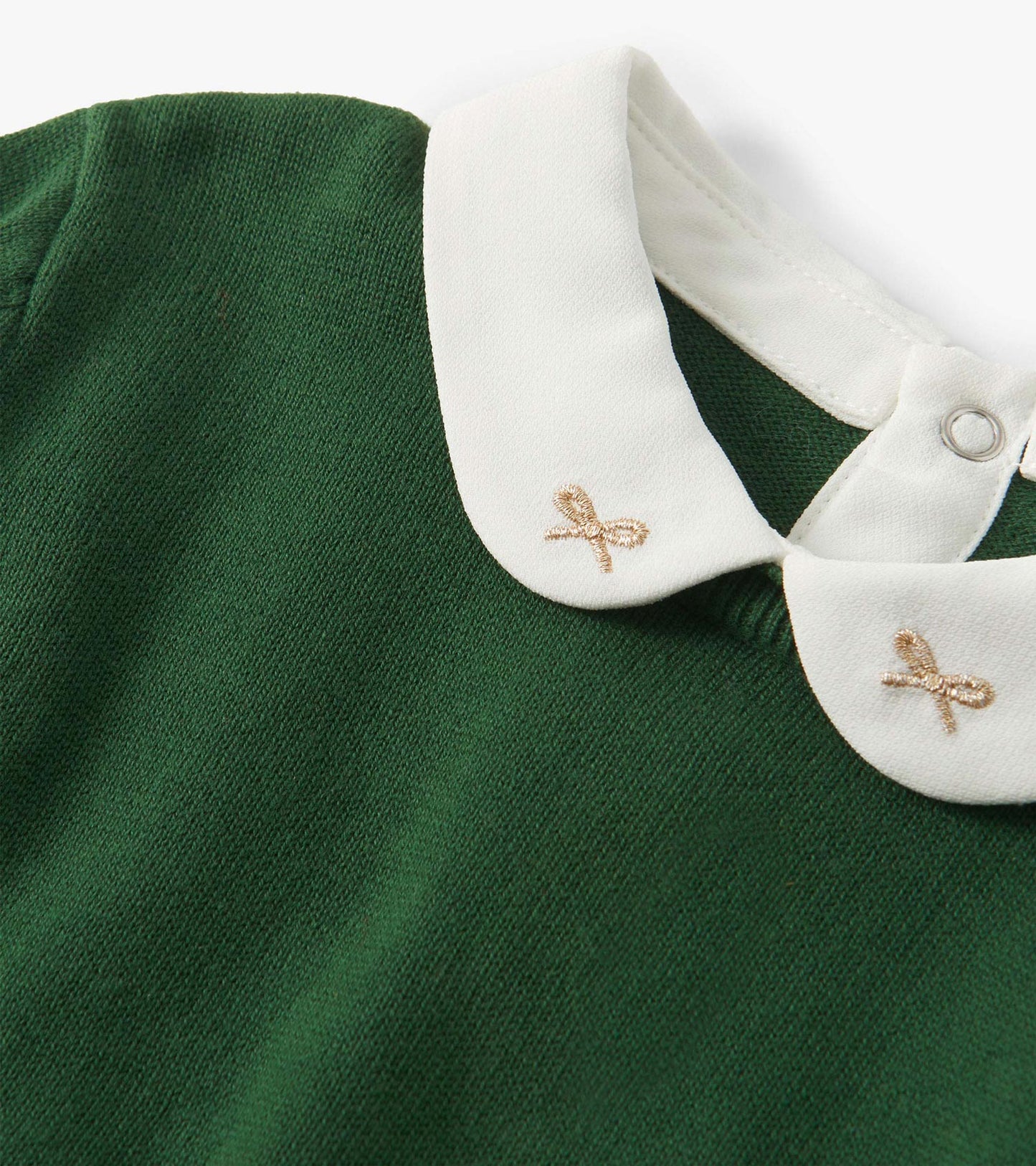 Close-up of a green knit sweater with a white Peter Pan collar and small embroidered bows