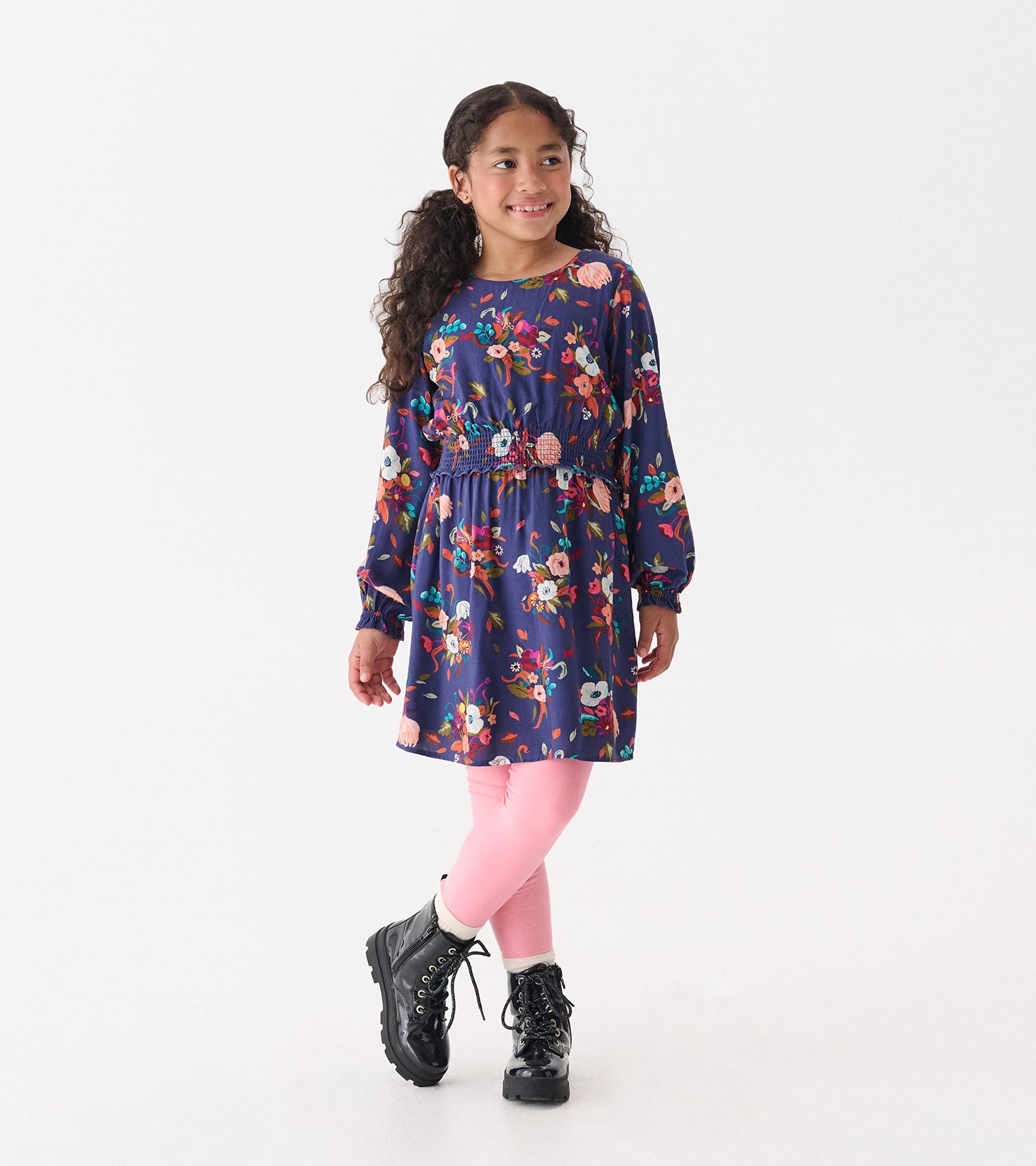 Navy floral dress with long sleeves and smocked waist, paired with pink leggings and black boots.