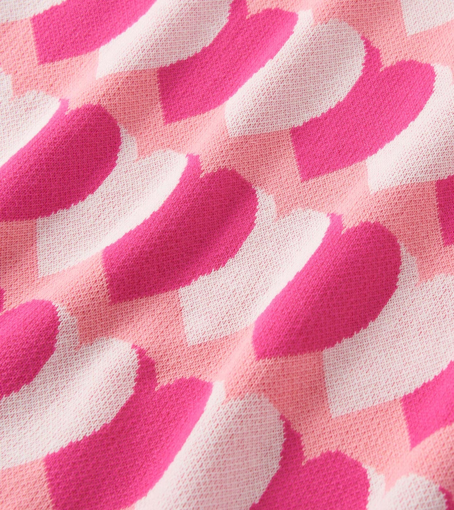 Pink sweater dress featuring a playful heart pattern in varying shades of pink and white. Soft, cozy knit material.