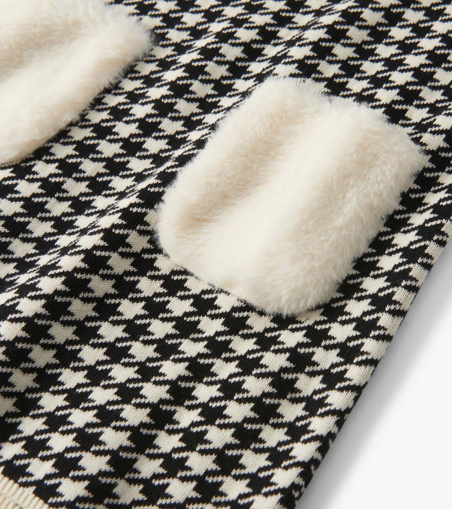 Black and white houndstooth knit dress with cream faux fur pockets, close-up detail