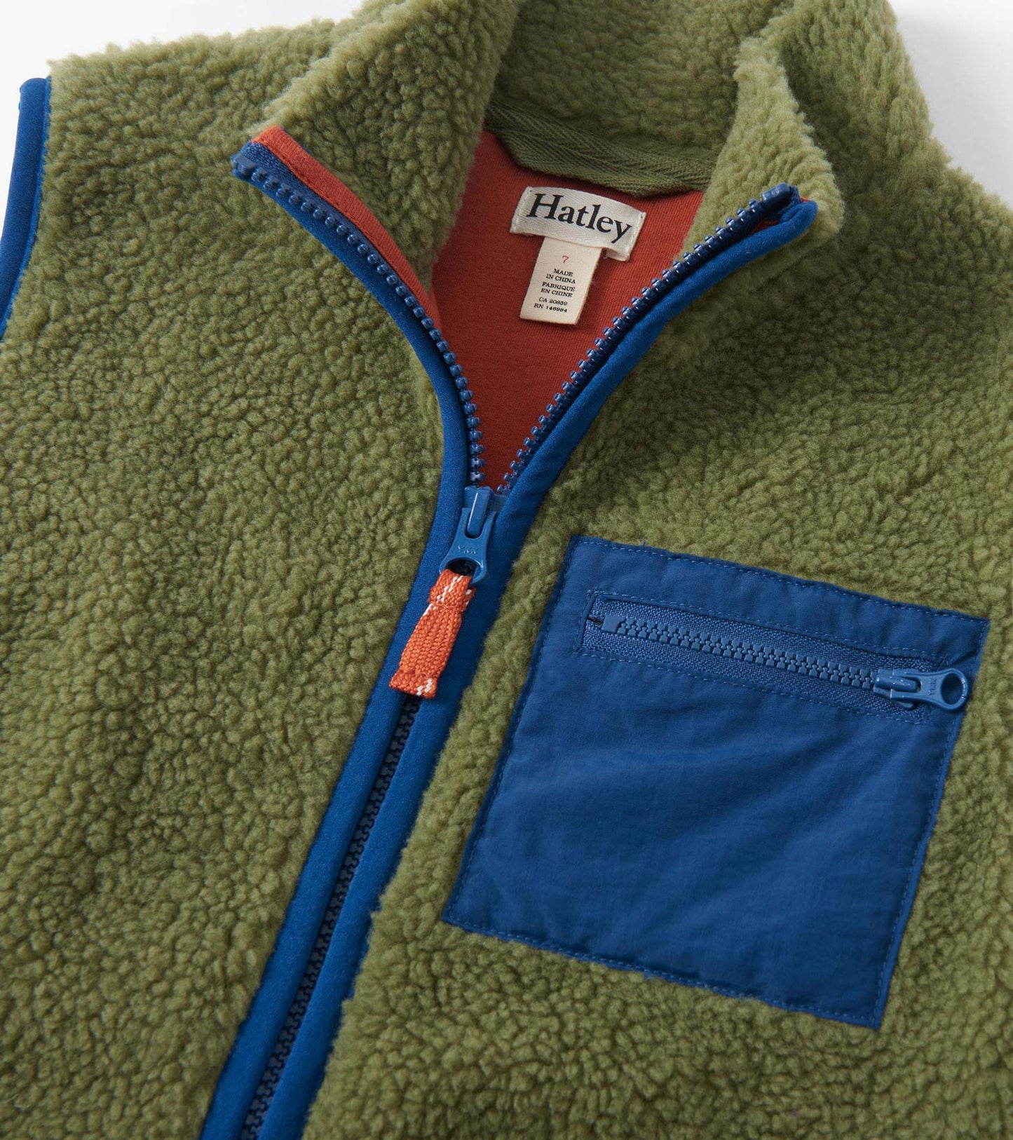 Loden green faux sherpa vest with a zip front, contrasting blue trim, and a small zippered pocket.