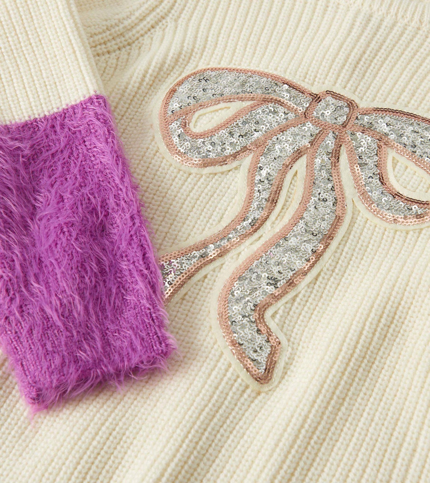 Cream sweater featuring fluffy purple sleeves and a sequined silver bow design.