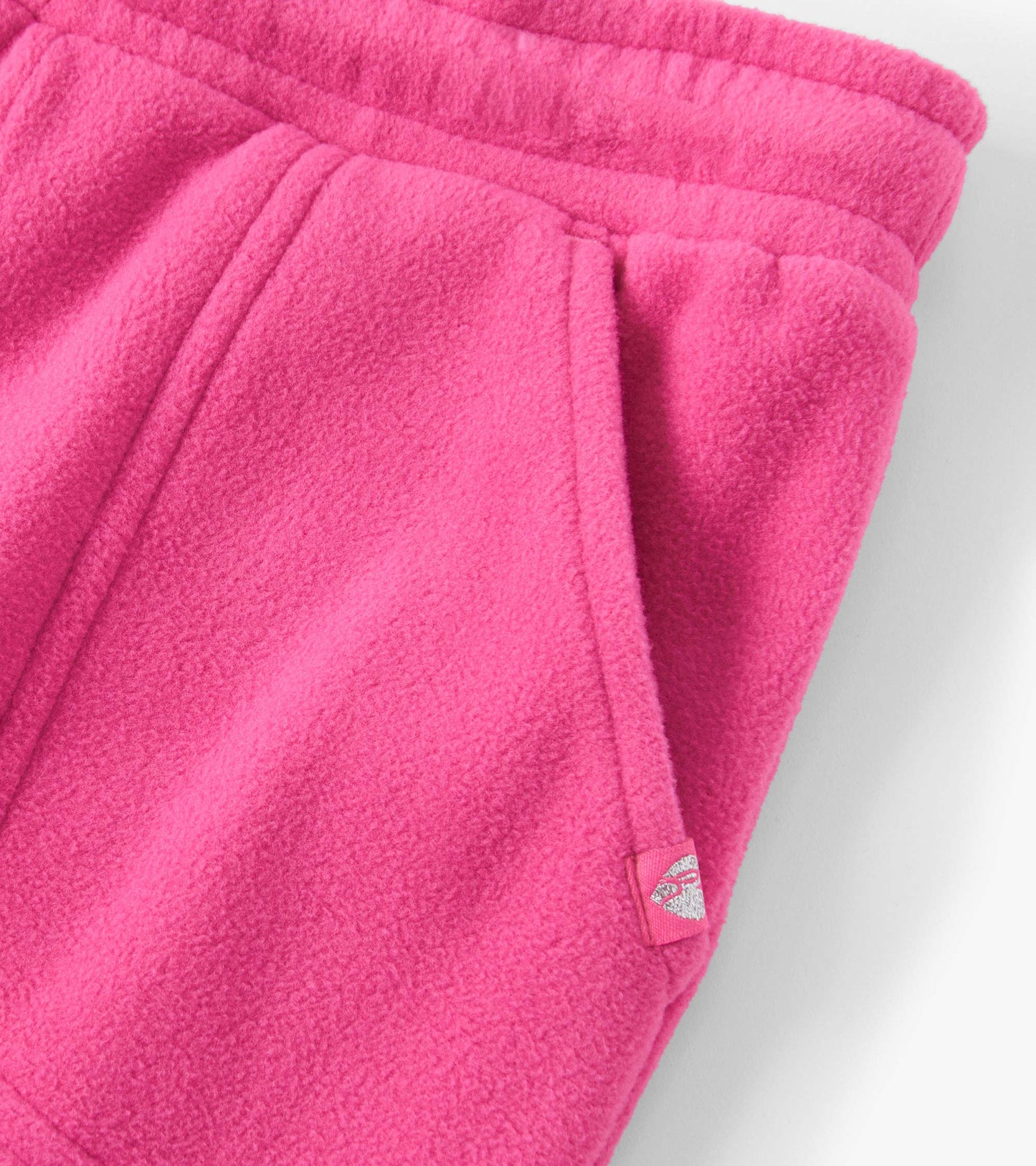 Bright pink polar fleece joggers with side pockets and an elastic waistband. Soft texture ideal for casual wear.