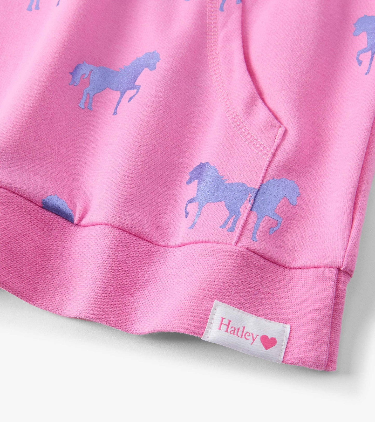Pink sweater featuring a pattern of blue shimmer horses, with a rounded neckline and ribbed hem.