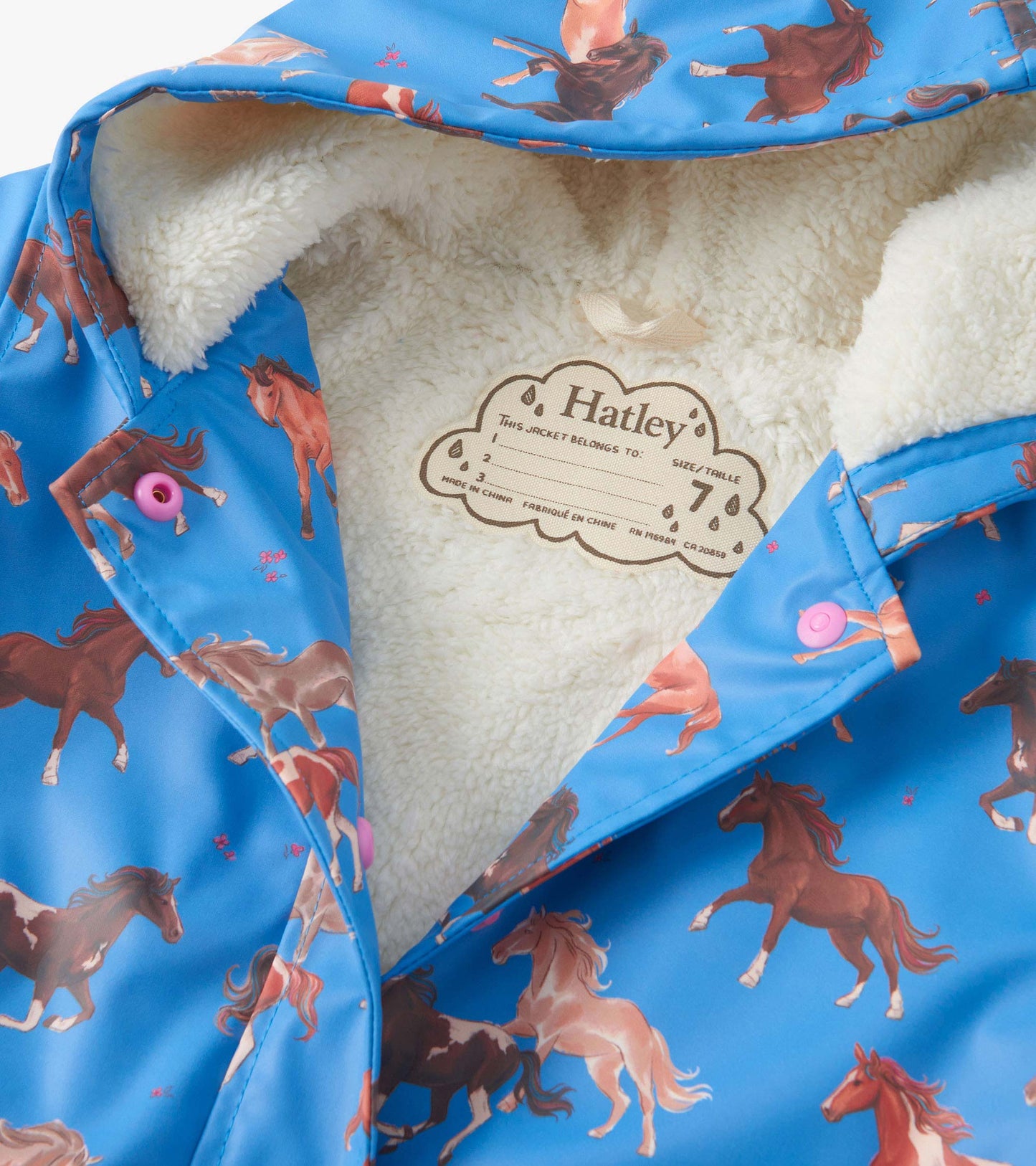 Blue raincoat with horse print, sherpa lining, and pink buttons, featuring a button-up design and hood.