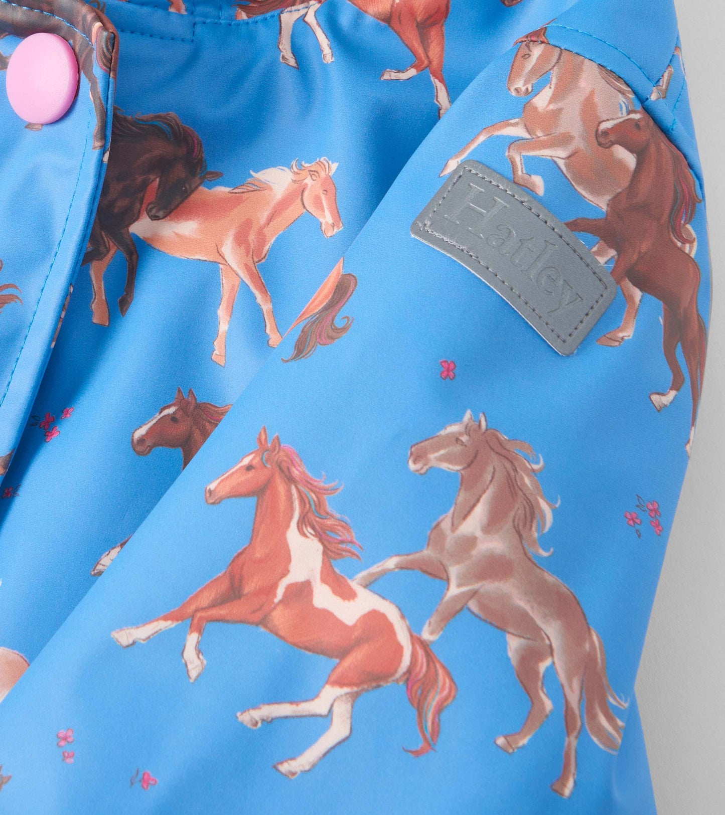 Blue raincoat featuring a playful horse print and pink button detail, designed for girls with a cozy sherpa lining.
