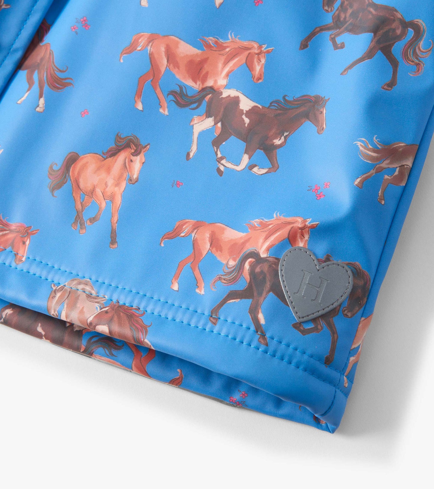 Blue raincoat featuring a playful horse pattern and a heart-shaped patch, designed for girls.