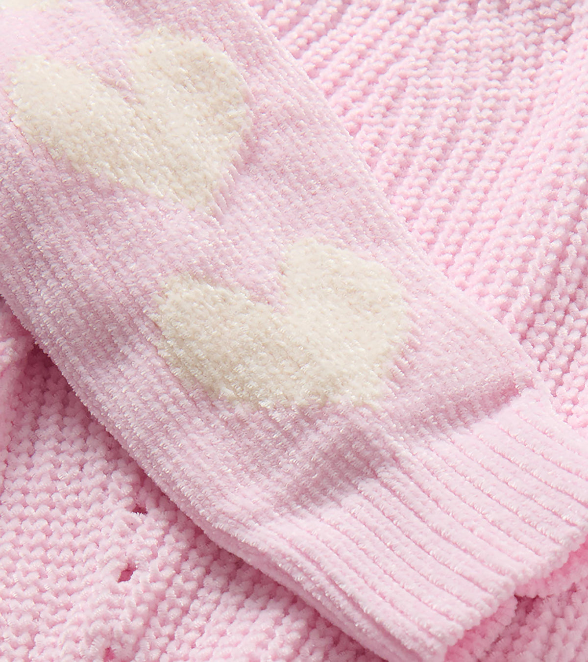Close-up of the pink knit sweater sleeve with cream heart pattern and ribbed cuff