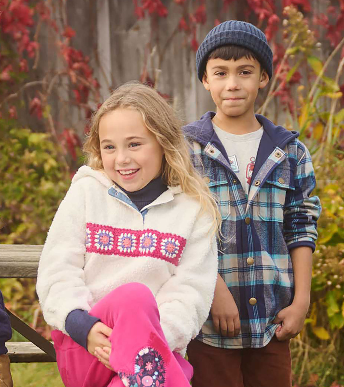 Boy wearing blue plaid hoodie shirt with snap front, standing outdoors beside another child