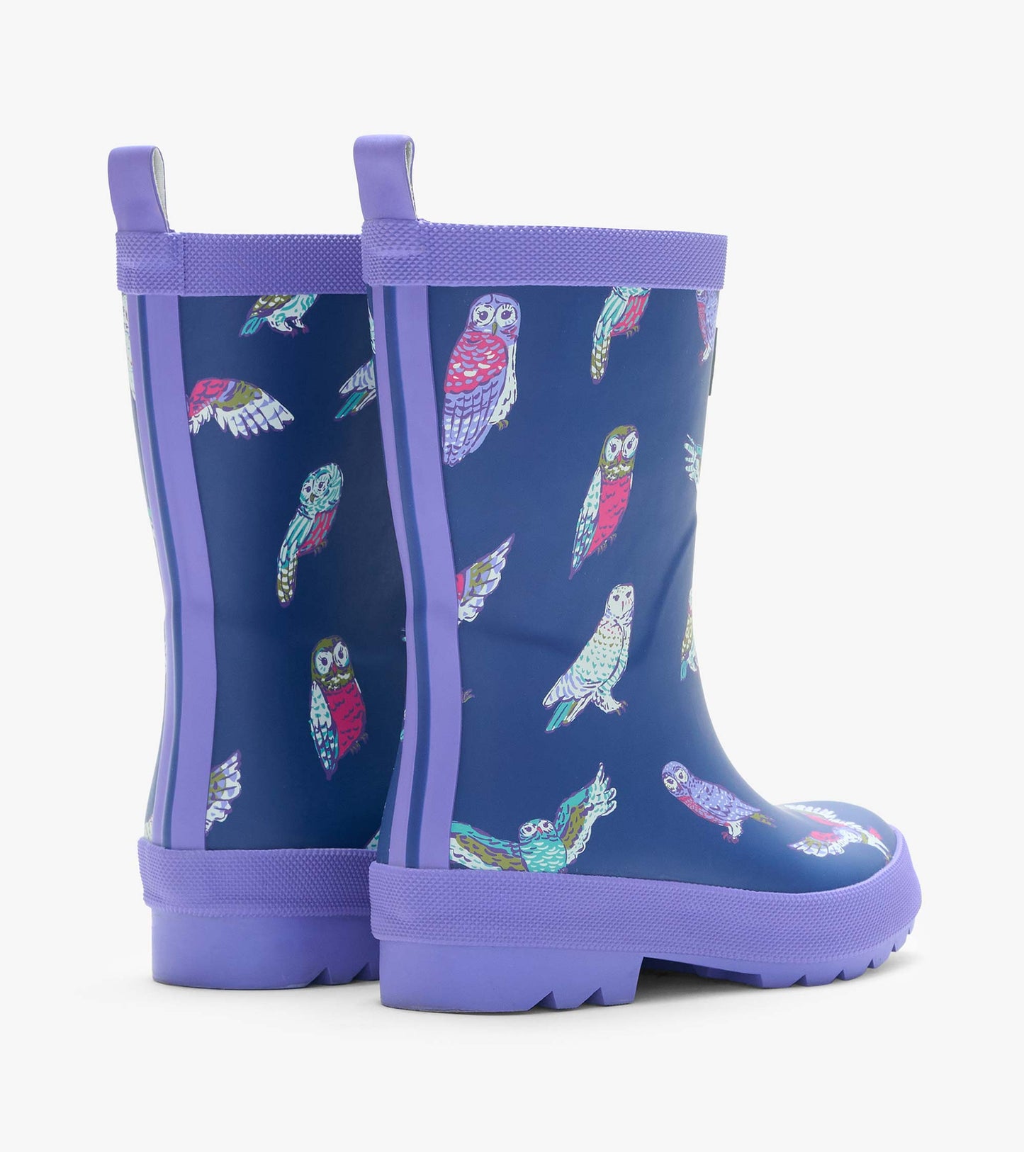 Rear angled view of navy kids rain boots with colorful owl print, purple trim, and back pull tabs