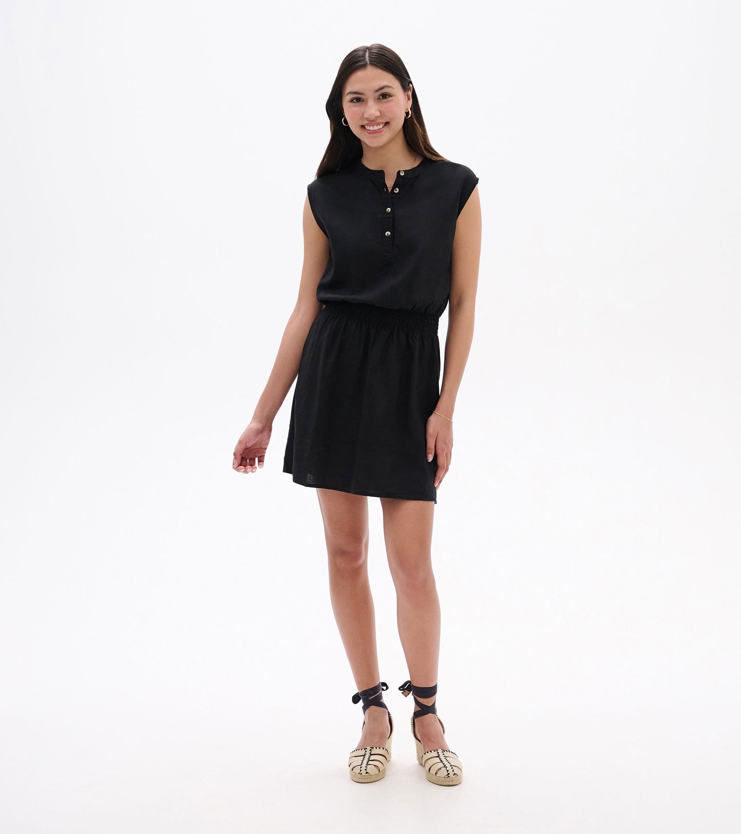 Black sleeveless dress with a buttoned neckline and elastic waist, styled for a casual look.