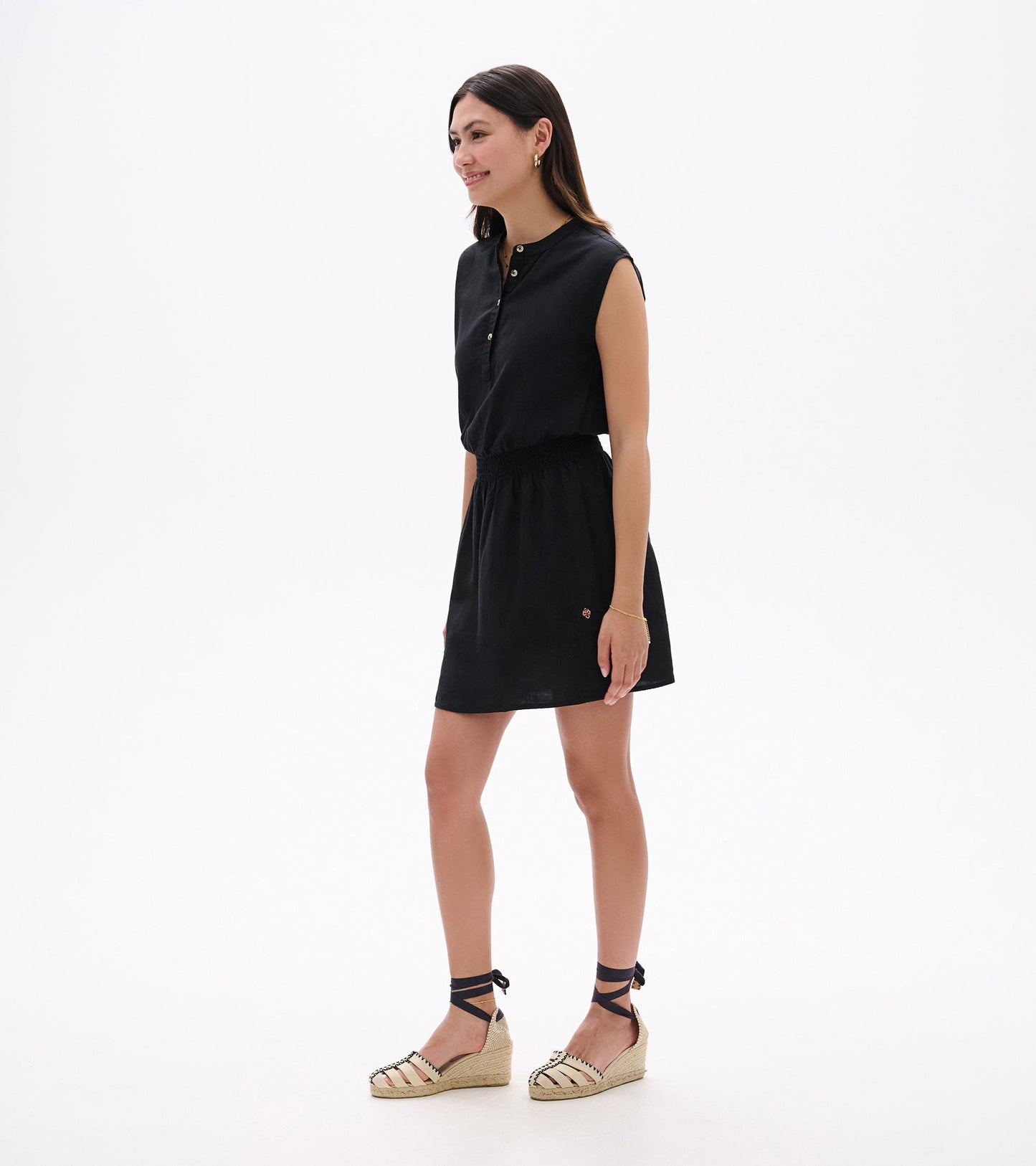 Black sleeveless dress with a buttoned collar and elastic waist, styled with espadrille wedges.