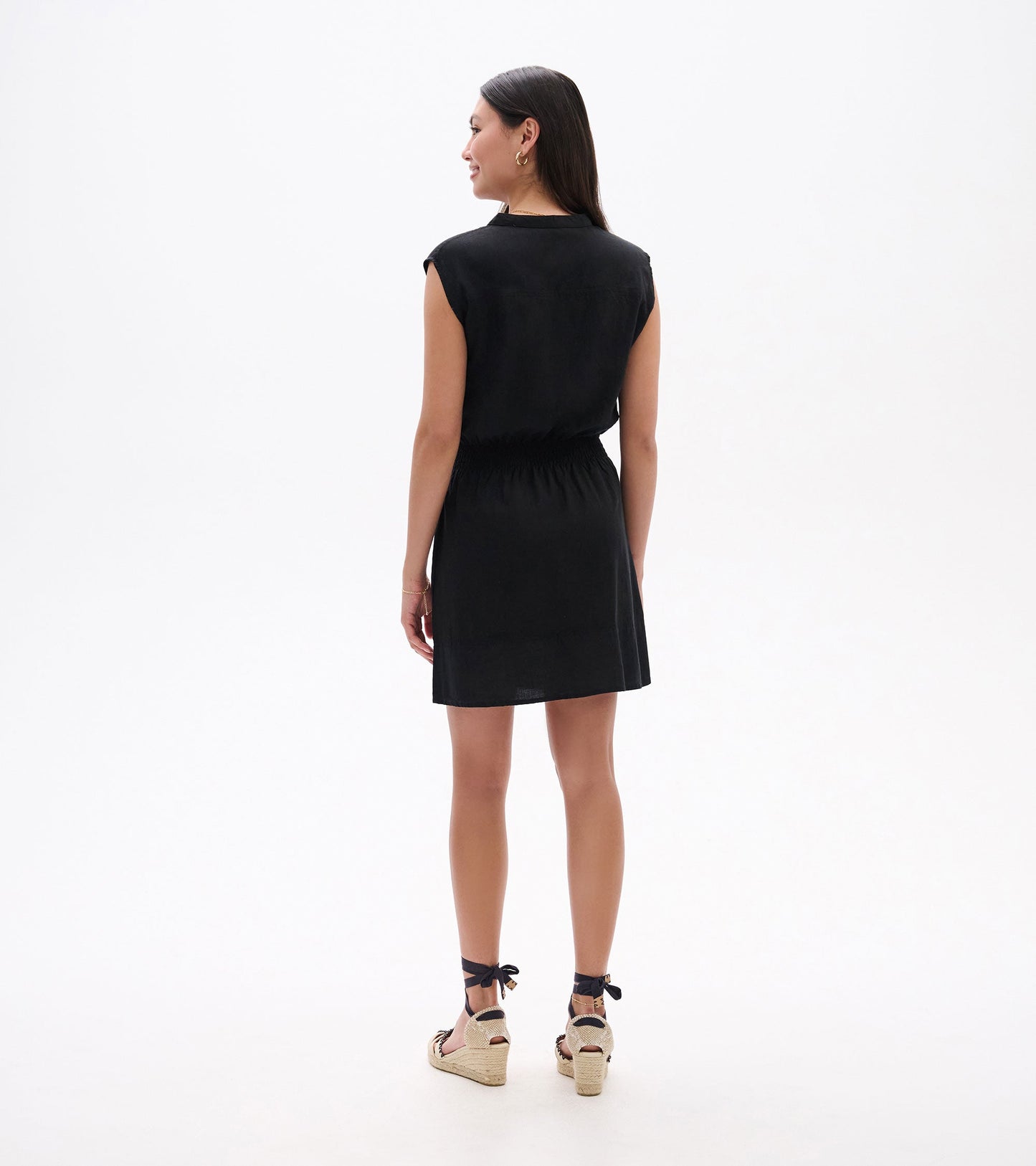 Black short-sleeve dress with an elastic waist, shown from the back, paired with espadrille sandals.
