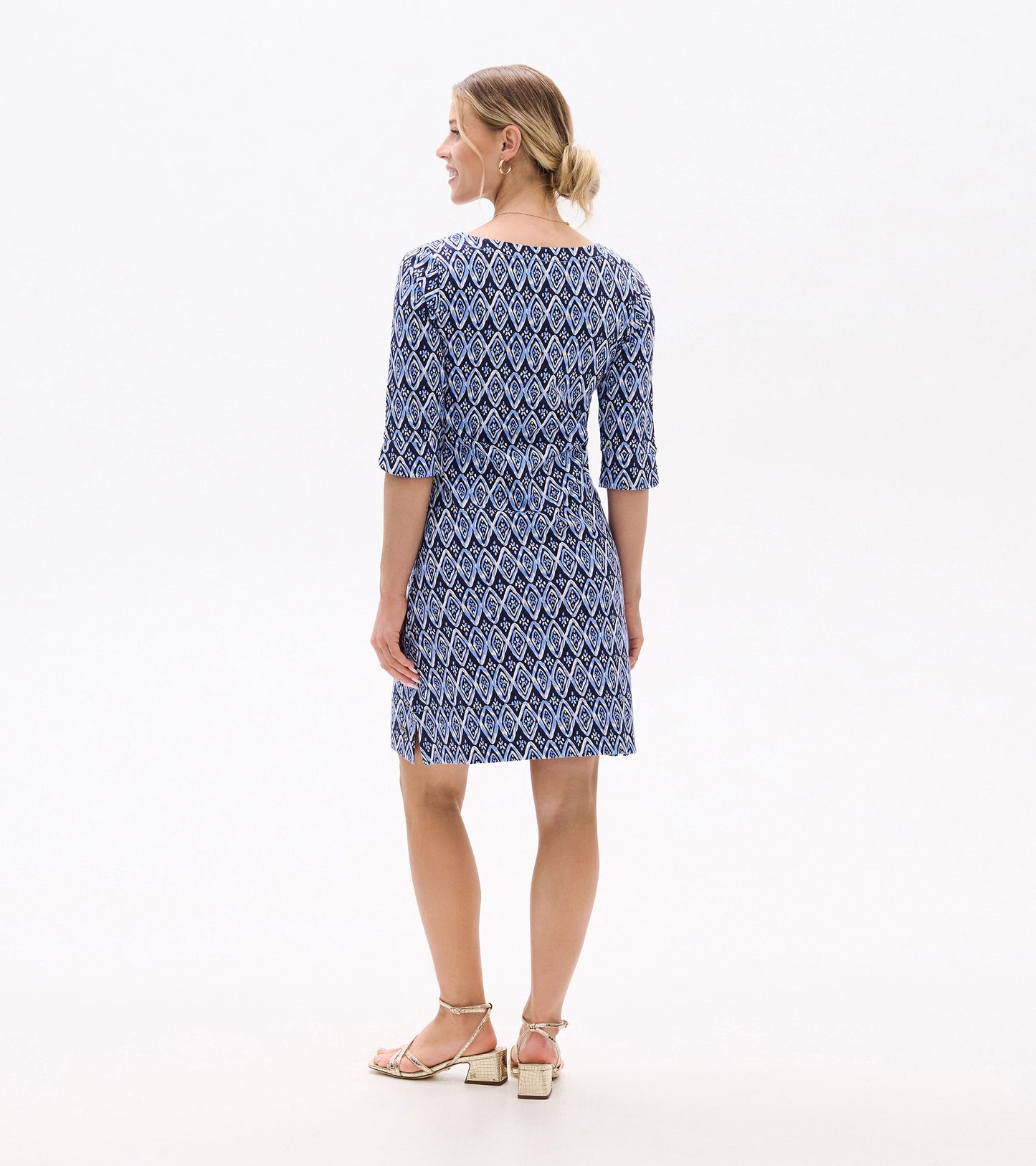 Back view of a short-sleeve dress featuring a blue and white diamond pattern, paired with strappy sandals.