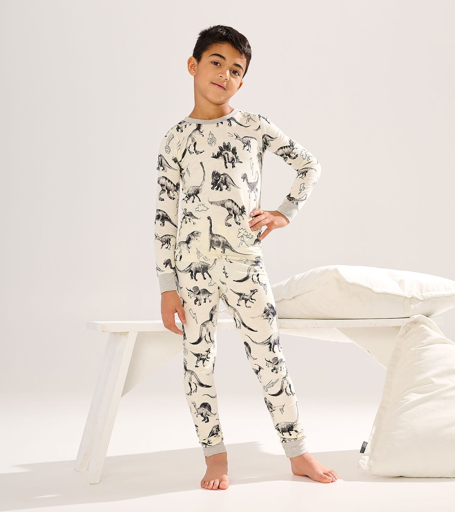 Long-sleeve pyjama set featuring a dinosaur print on a cream background, with grey cuffs and matching pants.
