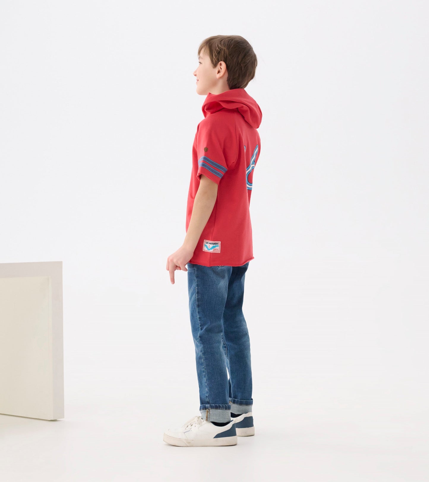 Red raglan hoodie tee with blue striped sleeves, featuring a relaxed fit and a hood, worn with denim jeans.