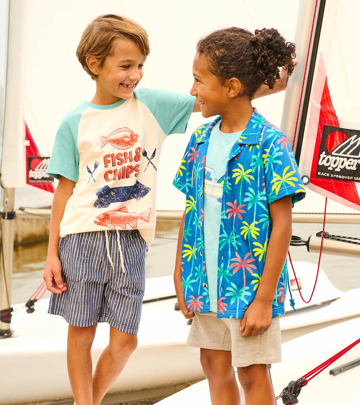 Boys' raglan t-shirt featuring a fish and chips graphic, cream body with teal sleeves, perfect for casual summer wear.