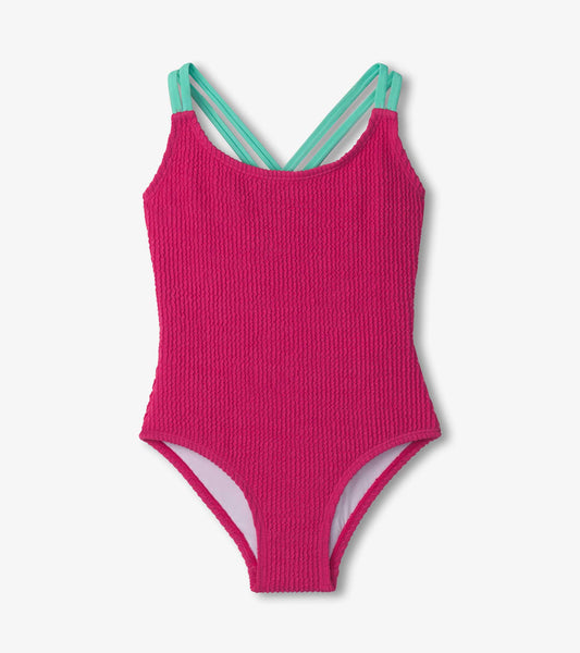 Fuchsia purple cross strap swimsuit with textured fabric and light blue straps, suitable for girls.