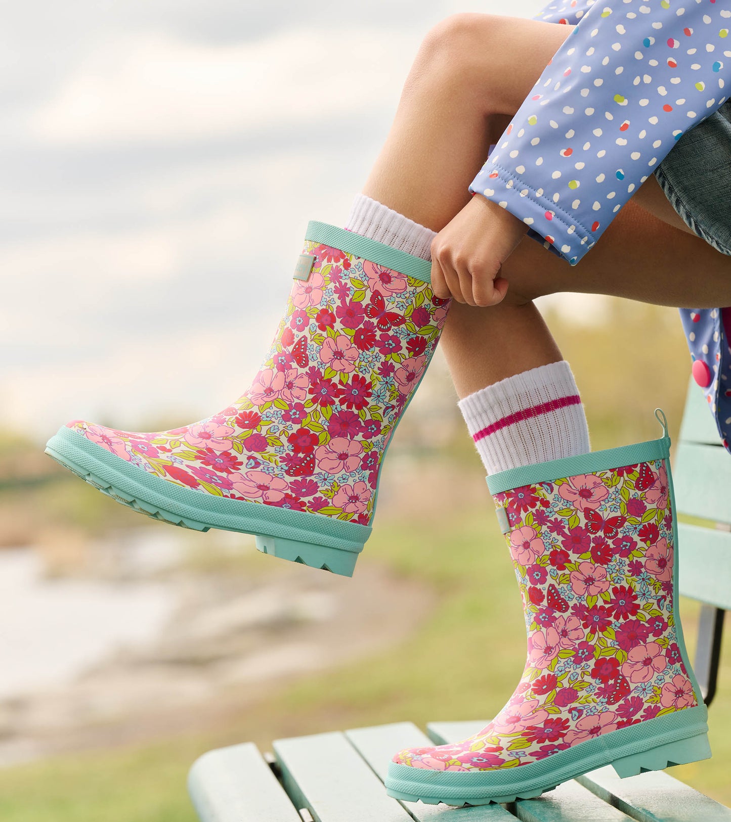 Pink floral matte wellies with a mint green sole, worn with white socks featuring pink stripes.