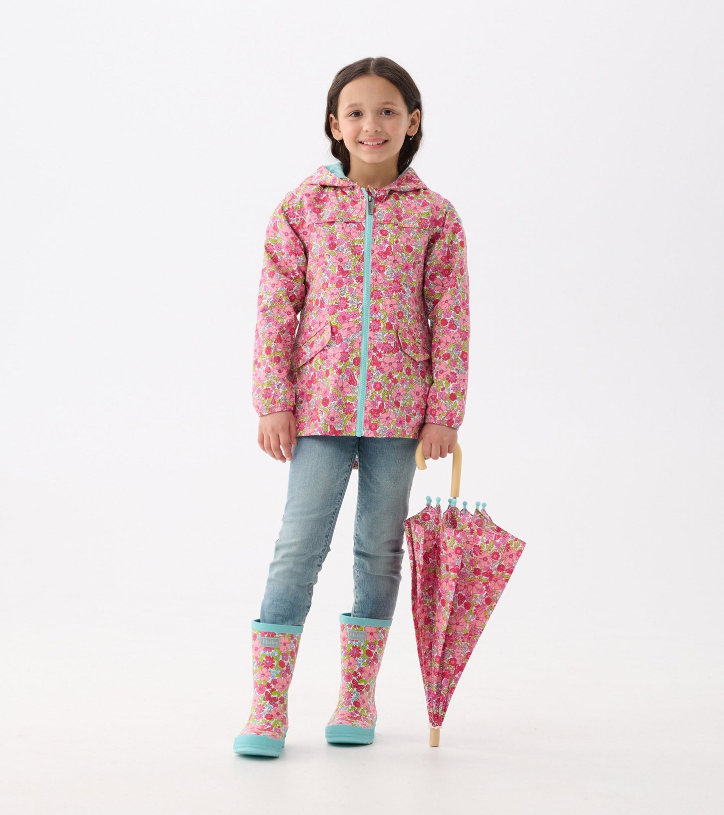 Matte wellies featuring a groovy flower pattern in pink and green, paired with a matching umbrella and casual outfit.