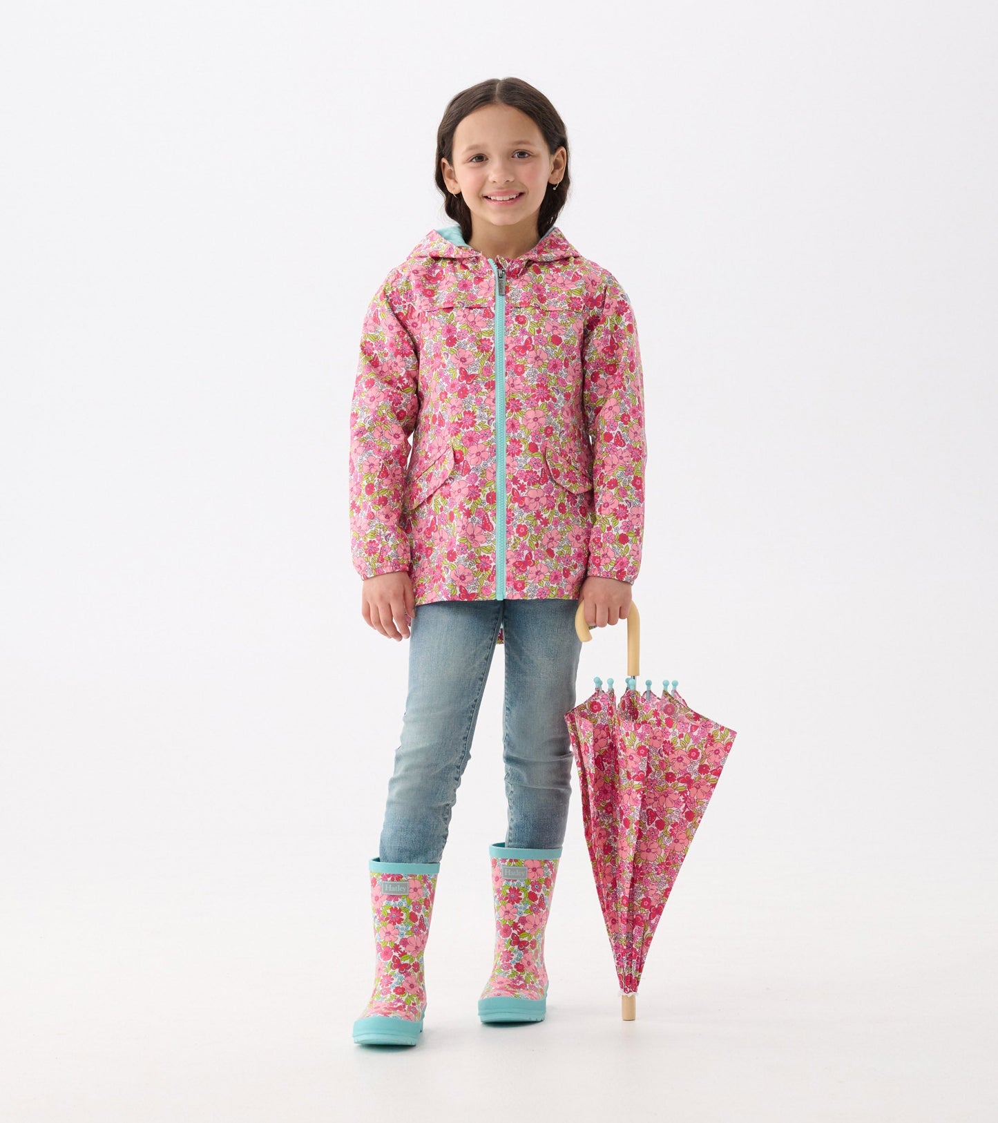 Lightweight pink raincoat with colorful floral pattern, paired with blue rain boots and a matching umbrella.