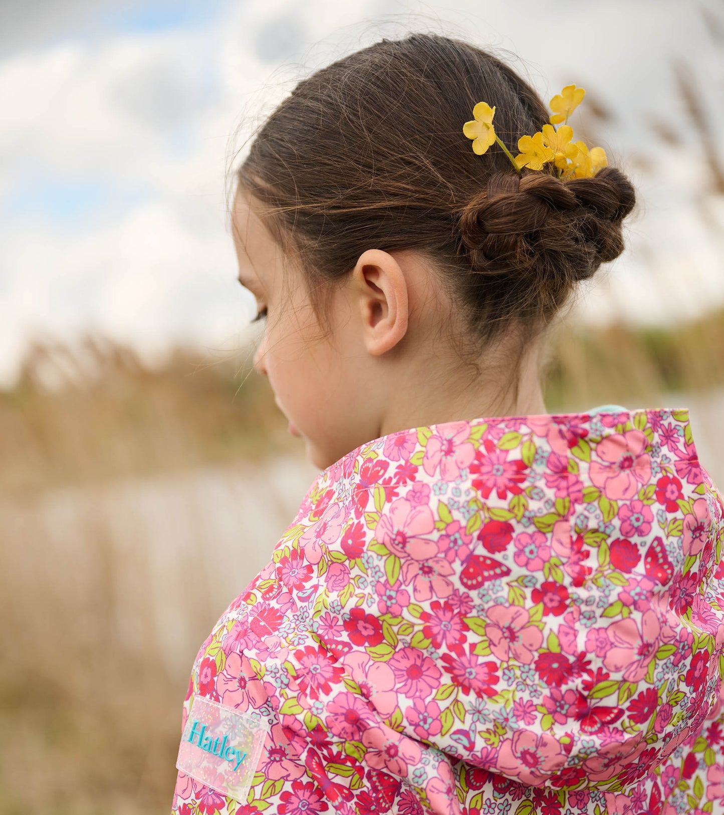 Lightweight zip-up raincoat featuring a vibrant pink floral pattern, perfect for girls. Shown from the back.