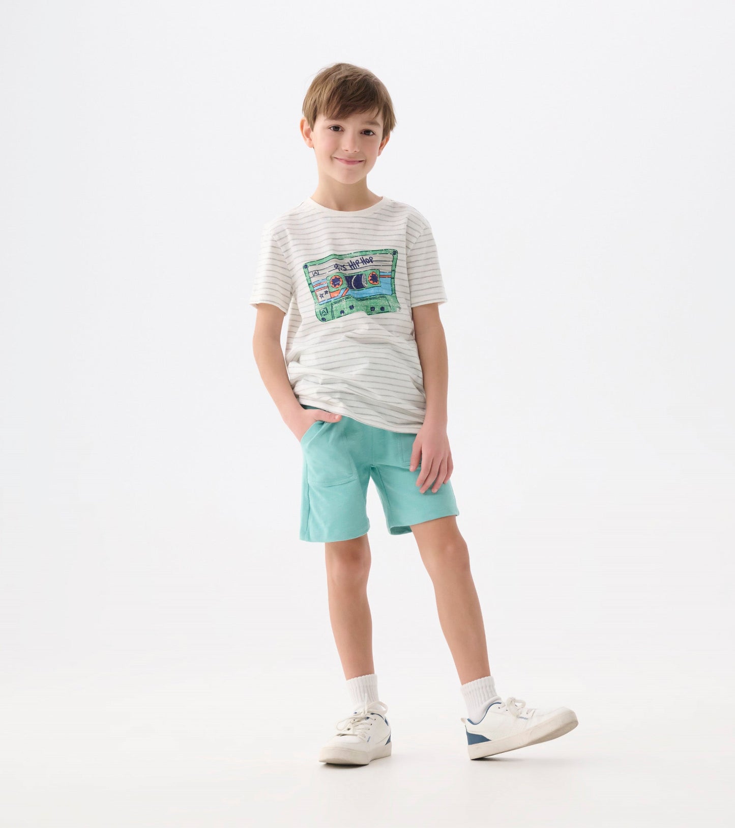 Striped graphic tee featuring a colorful cassette design, paired with mint green shorts, worn by a smiling boy.