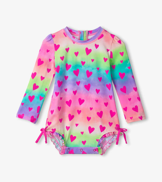 Long-sleeve swimsuit featuring a colorful gradient with pink hearts, designed for baby girls, with adjustable ties at the le…
