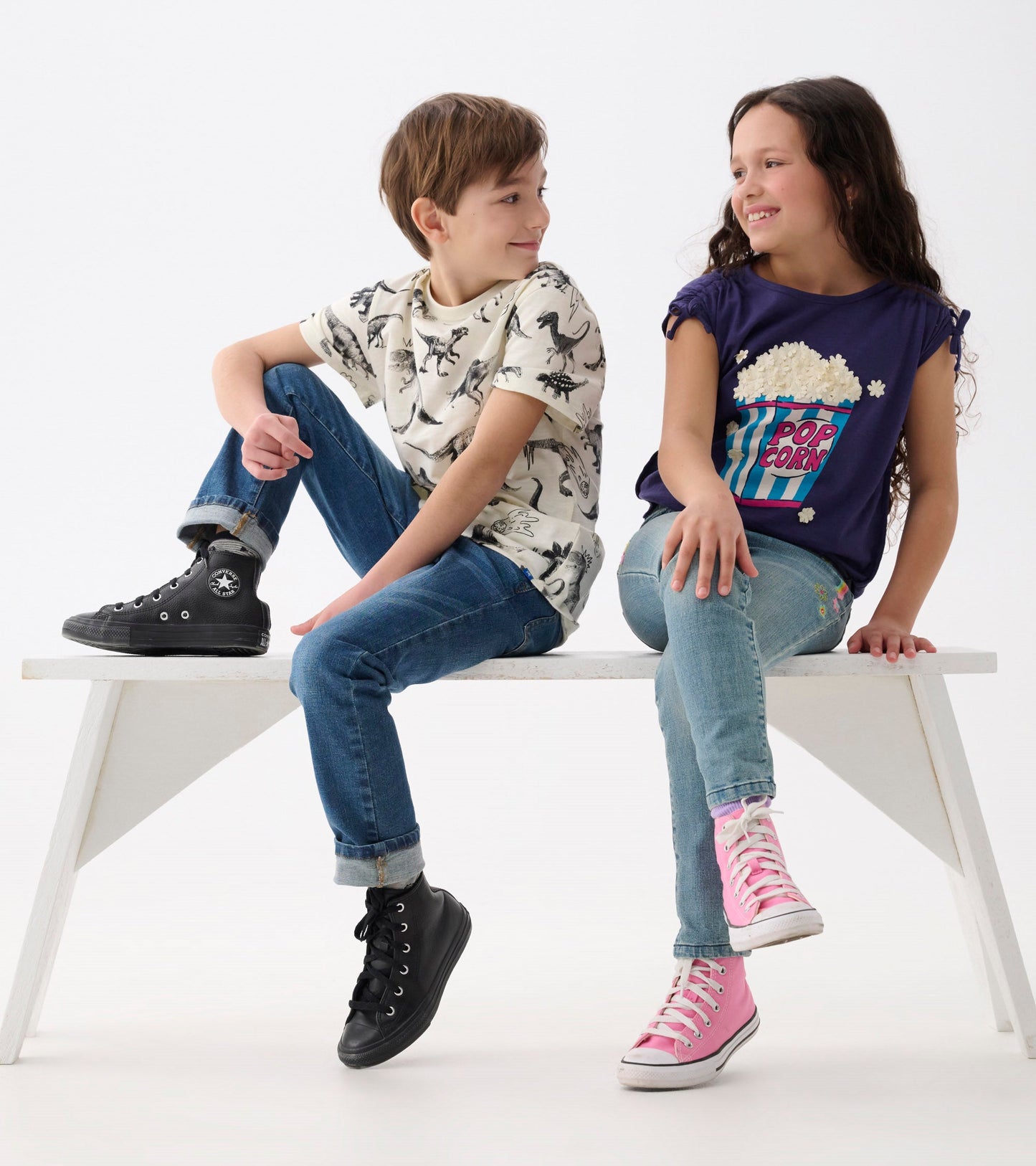 Navy cinched shoulder top featuring a popcorn graphic, paired with light blue jeans and colorful sneakers.