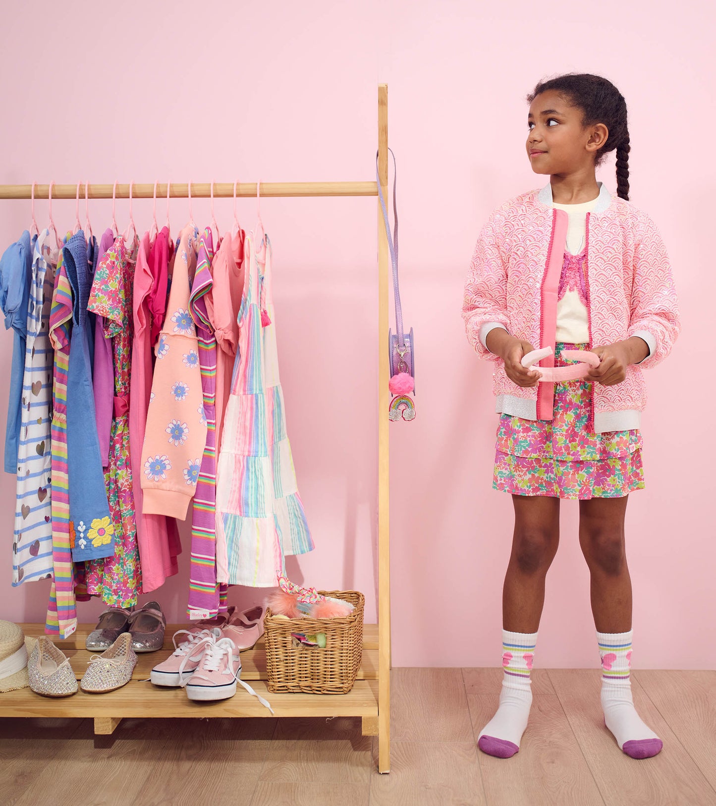 Pink sequined bomber jacket with mermaid pattern, worn by a girl, paired with a floral skirt and colorful socks.