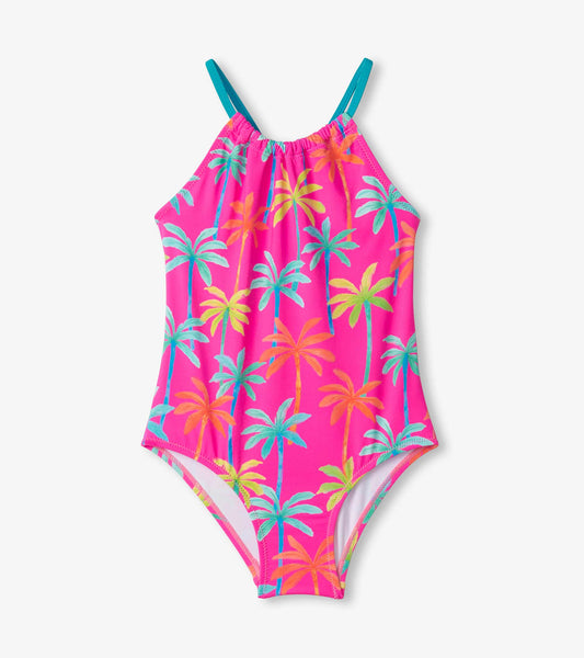 Bright pink swimsuit with gathered front, featuring colorful palm tree prints and adjustable teal straps.