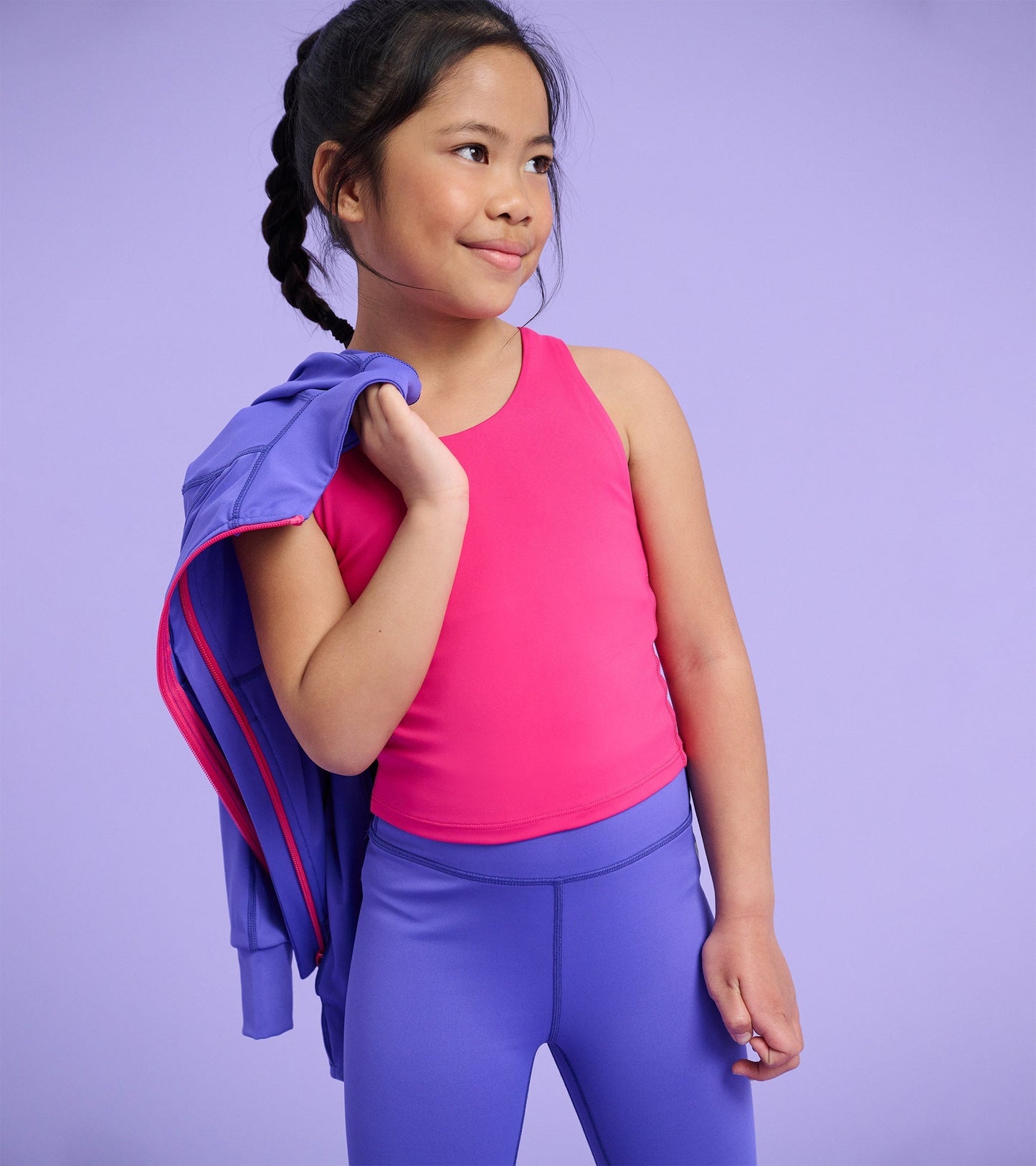 Bright pink tank top on a girl, paired with purple leggings, against a soft purple background.
