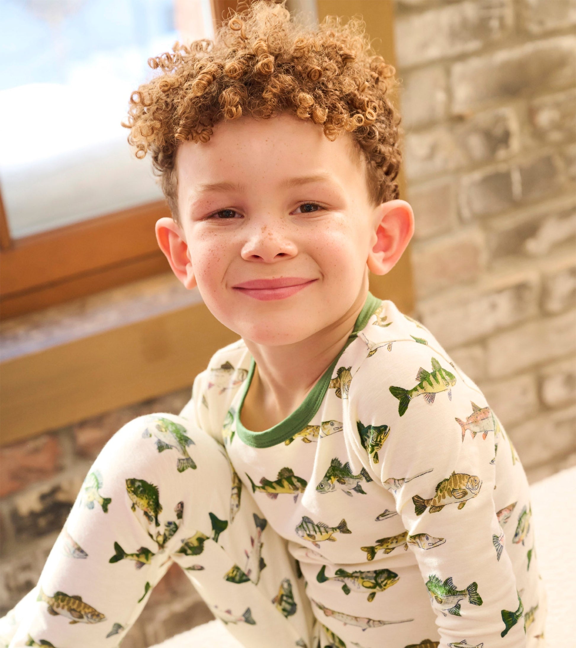 Boys' white pyjama set featuring colorful fish patterns, with green trim on the neckline and cuffs.