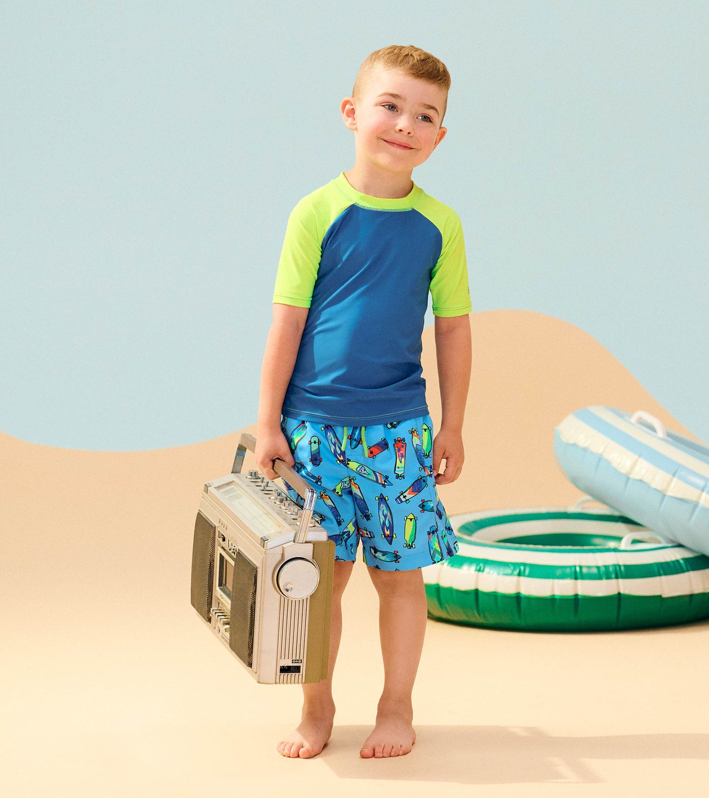 Short sleeve rashguard in blue with green accents, paired with colorful shorts, perfect for beach or pool activities.