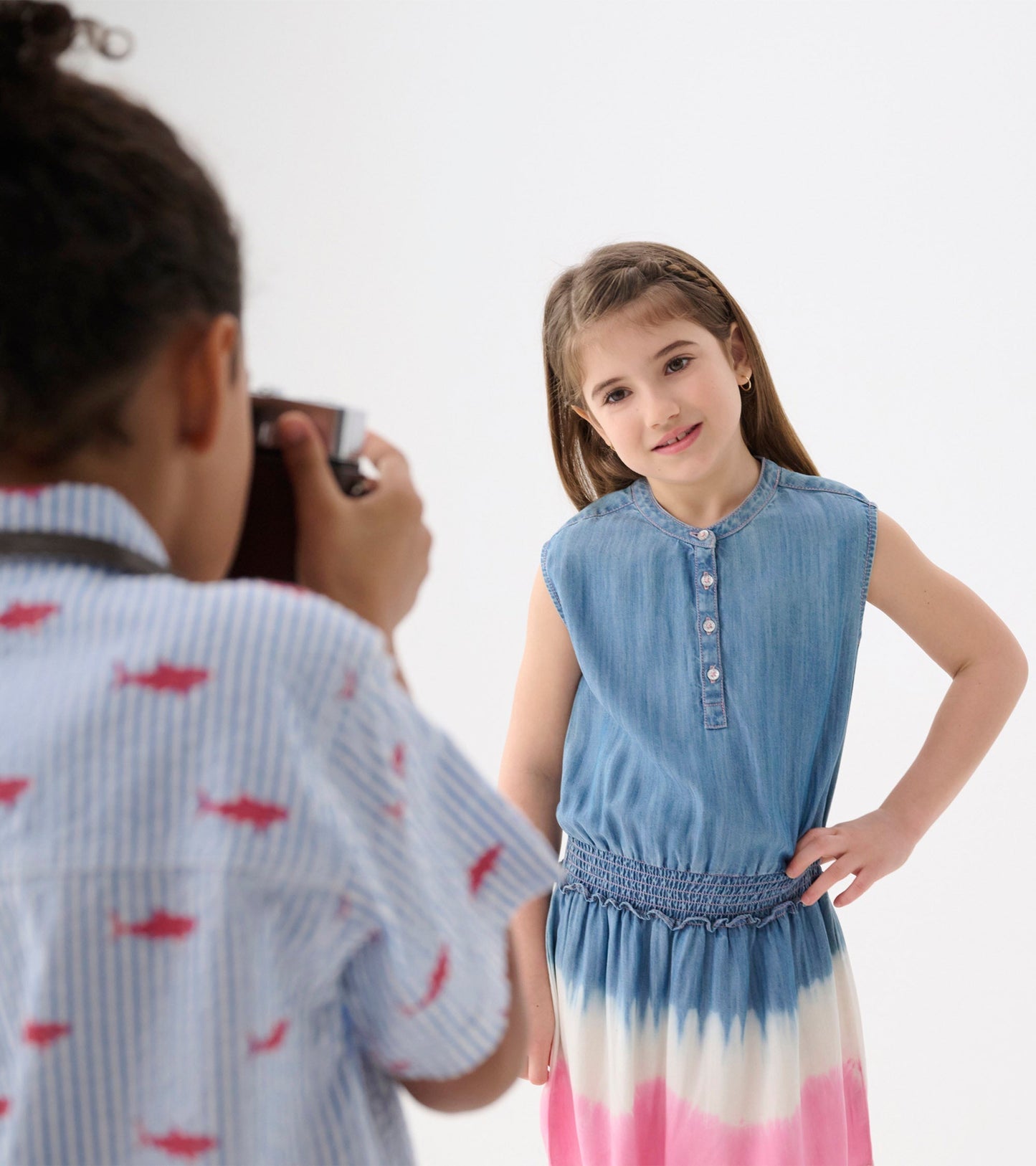 Light blue sleeveless dress with smocked waist and pink ombre pattern, styled for a girl.