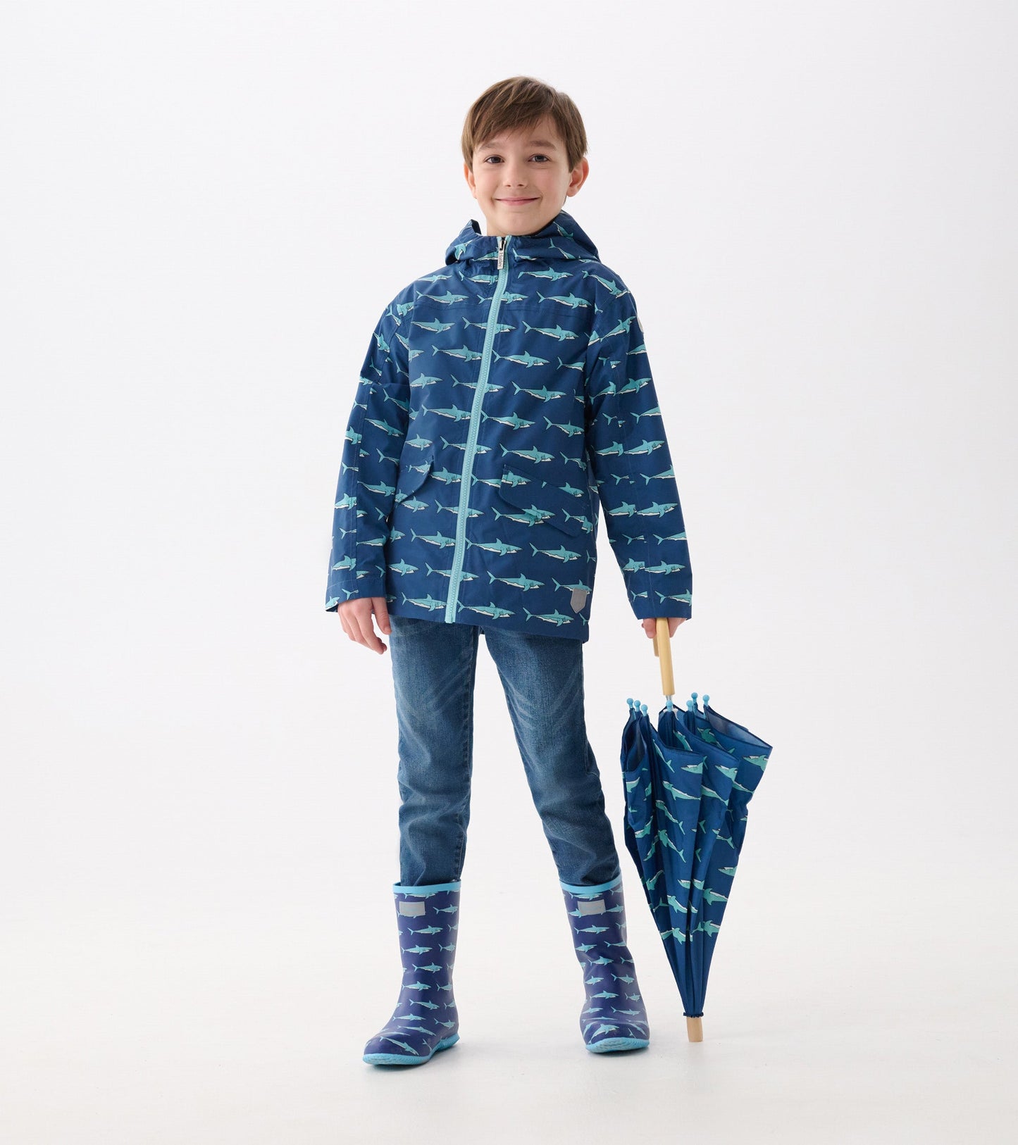 Lightweight navy raincoat with shark pattern, paired with blue jeans and matching rain boots, holding a shark-print umbrella.
