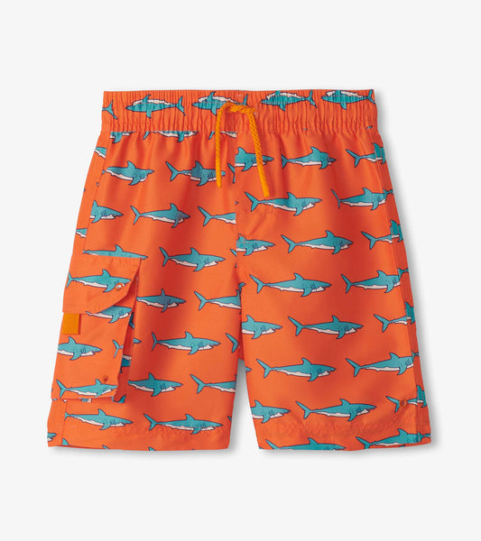Orange board shorts featuring a shark pattern, with an elastic waistband and side pocket. Ideal for beach or pool wear.