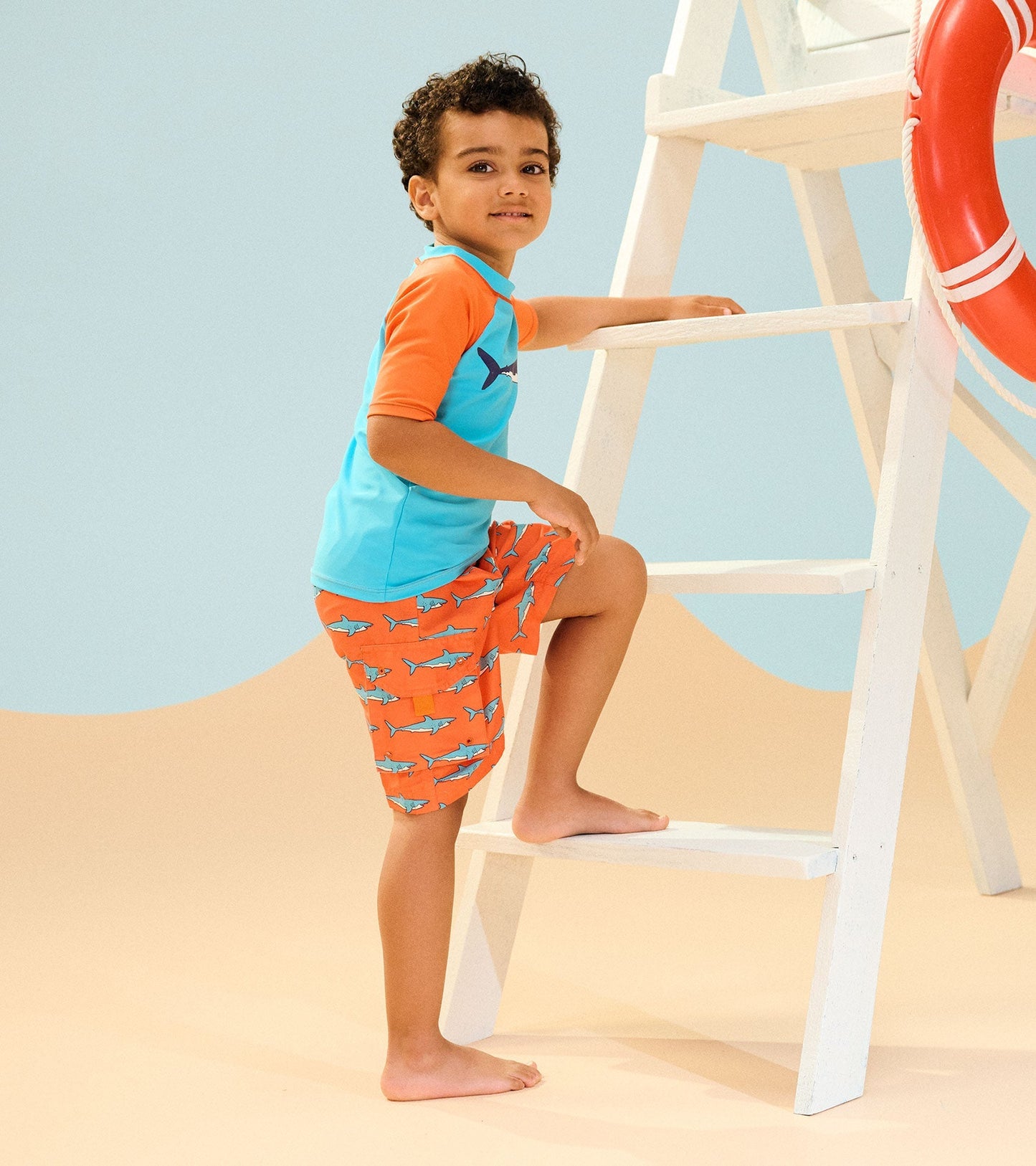 Boys' board shorts featuring a vibrant orange color with shark patterns, perfect for beach or pool activities.
