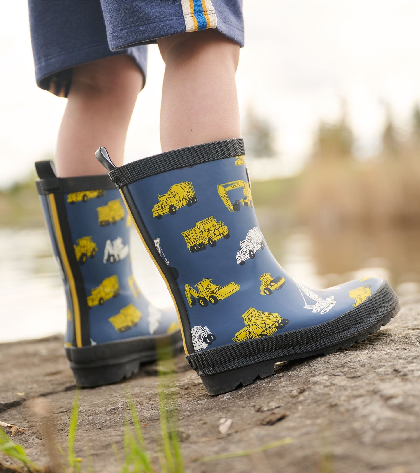 Matte blue wellies featuring yellow construction vehicle patterns, ideal for outdoor play.
