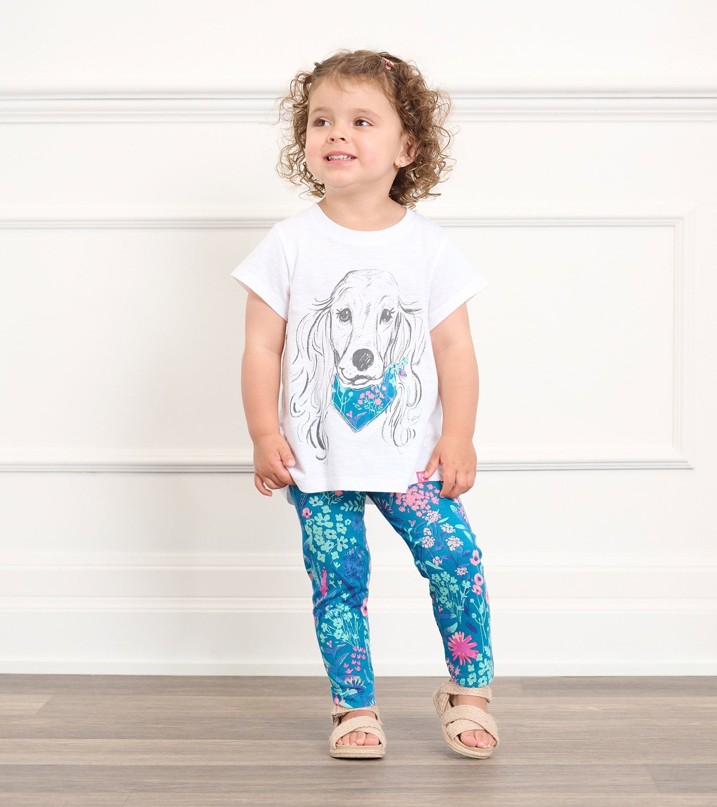 Blue bamboo leggings with a wildflower pattern, paired with a white shirt and sandals, worn by a smiling toddler.
